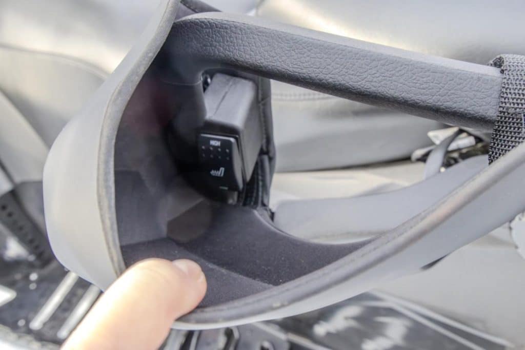 Close-up of a heated passenger hand grip control switch integrated into the rear seat handle of an Arctic Cat snowmobile.
