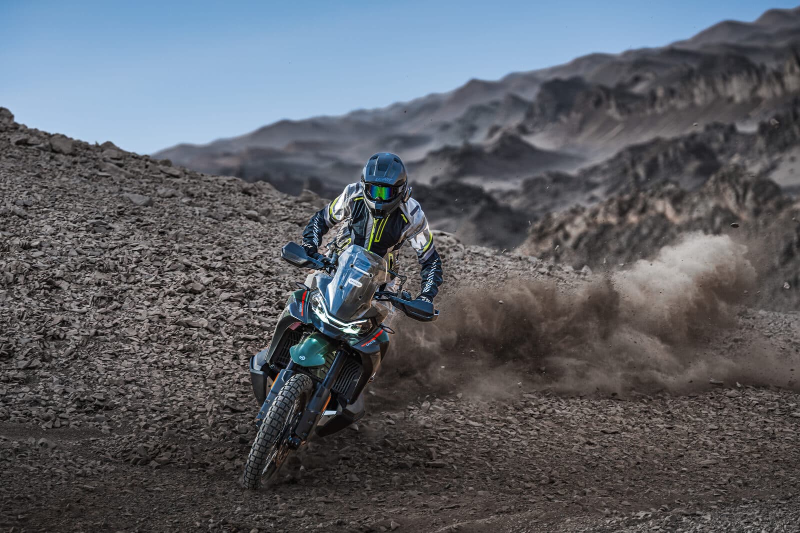 A 21-inch front wheel and long-travel suspension signal genuine off-road intent.
